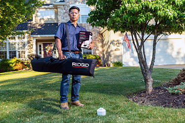 Man carrying RIDGID pipe patch system to a residence.